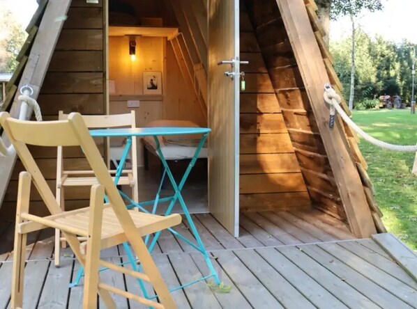 A wooden tent with a table and chairs outside.