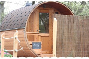 Eine Holzhütte mit gewölbtem Dach, einer Tür und einer kleinen Holzbank davor.
