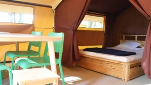 Um quarto com tenda, uma cama, uma mesa e cadeiras.