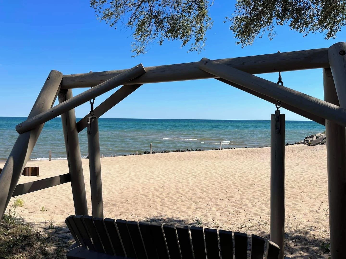 A wooden swing set overlooking a sandy beach with the ocean in the background.