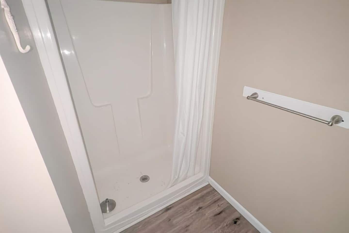 Une salle de bain avec une douche, un porte-serviettes et un plancher en bois.