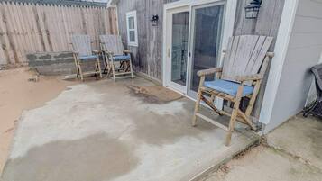 A concrete patio with two wooden chairs and a door with a glass panel.