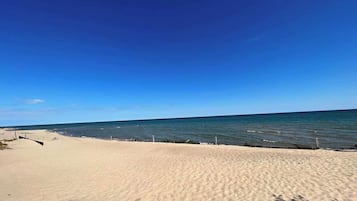 A sandy beach with a clear blue sky and calm sea.