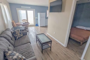 A living room with a sofa, a coffee table, and a TV mounted on the wall.