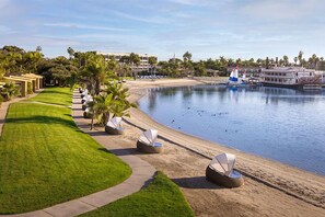 Ein Strandhotel mit gepflegtem Rasen, Liegestühlen und einer Bootsanlegestelle.
