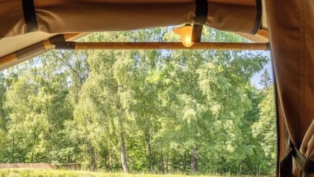 Puinen terassi, jossa on pöytä ja tuoleja, ja josta avautuu näkymä vesistöön ja puustoon.