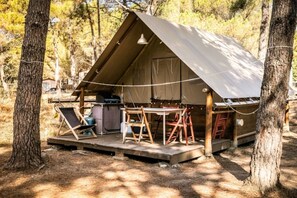 Ein kleines Ein-Zimmer-Zelt mit flachem Dach, einem Tisch, Stühlen und einer kleinen Küchenzeile.