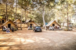 Ein Campingplatz mit mehreren Zelten, einer unbefestigten Straße und einem geparkten Auto in der Mitte.