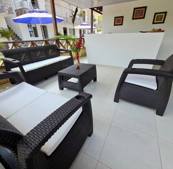 A patio area with wicker furniture, including sofas and chairs, a small table, and a decorative plant.