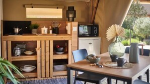 Une cuisine compacte équipée d’un four à micro-ondes, d’une bouilloire et d’étagères en bois.