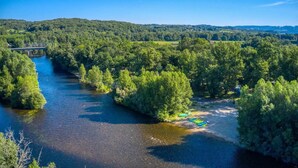 Une rivière bordée d’une for êt dense, un pont et un ciel dégagé.