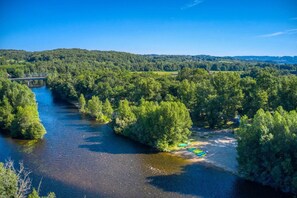 Ein Fluss, umgeben von dichtem Wald, eine Brücke und ein klarer Himmel.