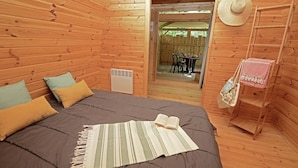 Habitación de cabaña de madera con cama, almohadas, un radiador, una escalera y un sombrero en la pared.