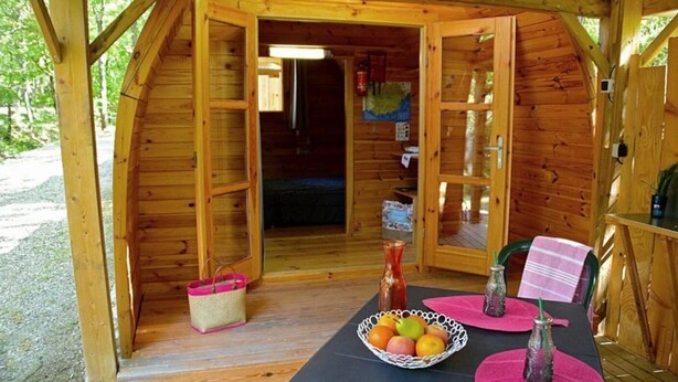 Una cabaña de madera con comedor, una cesta y un frutero.
