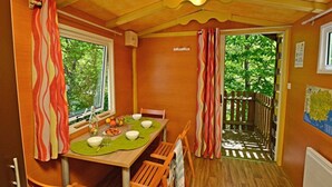 Een eetgedeelte met een tafel voor vier personen, een raam en uitzicht op een houten terras.