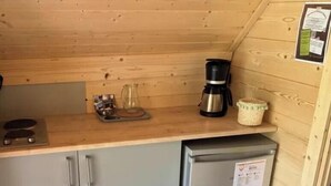 A compact kitchen with a built-in refrigerator, a coffee maker, and a kettle on the countertop.