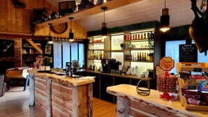 A rustic bar area with wooden furniture, a coffee machine, and a variety of beverages on shelves.