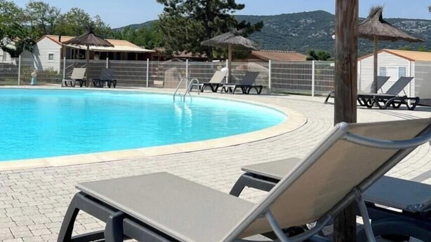 A swimming pool with lounge chairs and umbrellas, surrounded by a fence and trees. - ZEcamping 3* piscine pet friendly chalet 3 pers (Saint-Remèze)