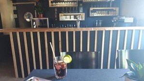 A bar area with a counter, shelves of glasses, and a plate of food with a drink. - ZEcamping 3 étoiles piscine chauffée pataugeoire locatif 12m2 3 pers (Vendoire)