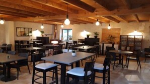 A spacious dining area with wooden beams, tables, and chairs arranged for dining.