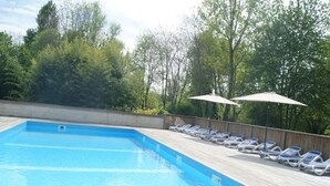 A swimming pool with a wooden deck and lounge chairs.