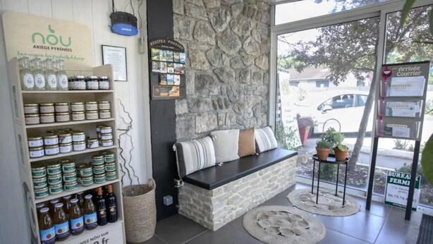 Un interior acogedor con una pared de piedra, una zona de estar con cojines y una exhibición de frascos y botellas.