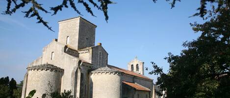 Una iglesia de piedra histórica con un campanario y un edificio adyacente más pequeño.