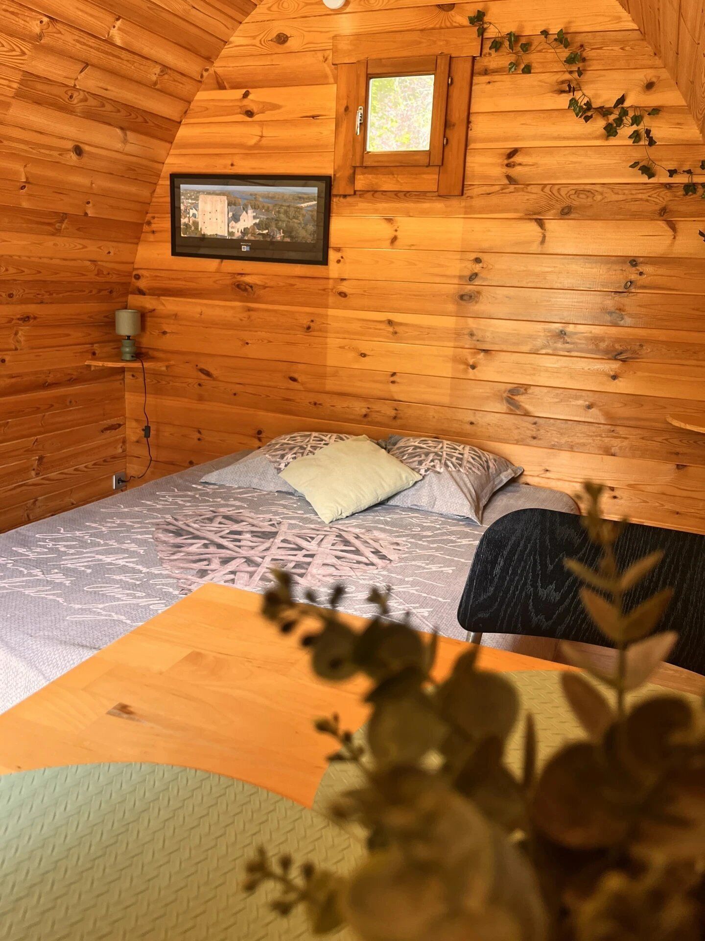Una habitación acogedora de estilo cabaña con una cama, una ventana pequeña y un cuadro enmarcado en la pared.