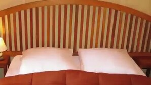 Een bed met een houten hoofdeinde, twee kussens en een bruine deken.