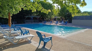 Una piscina con lettini da spiaggia e una zona relax coperta.