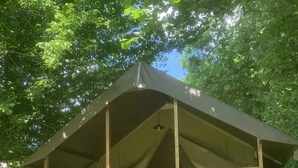 Un pabellón de madera con techo cubierto, una escalera y una zona de estar.
