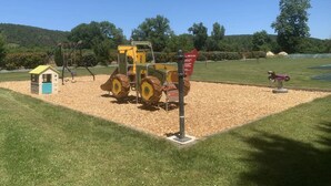 Un parque infantil con un tractor, una casita y columpios.