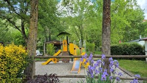 A playground with yellow equipment surrounded by trees and purple flowers. - ZEcamping 3* piscine pet friendly Tente tribu 4 pers (Belmont-sur-Rance)