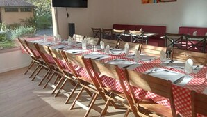 A dining area with tables set for four, wooden chairs, and a television mounted on the wall. - ZEcamping 3* piscine pet friendly Tente tribu 4 pers (Belmont-sur-Rance)