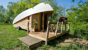 A dome-shaped wooden cabin with a wooden deck, a small table, and a chair. - ZEcamping piscine chauffée pet friendly locatif BBQ 4 pers (Chassenard)