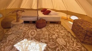 A tent with a bed, pillows, a hanging light, and a woven basket. - ZEcamping 3 étoiles piscine animaux acceptés tente 12m2 2 pers (Tuchan)