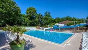 En swimmingpool med rutsjebane, liggestole og en potteplante.