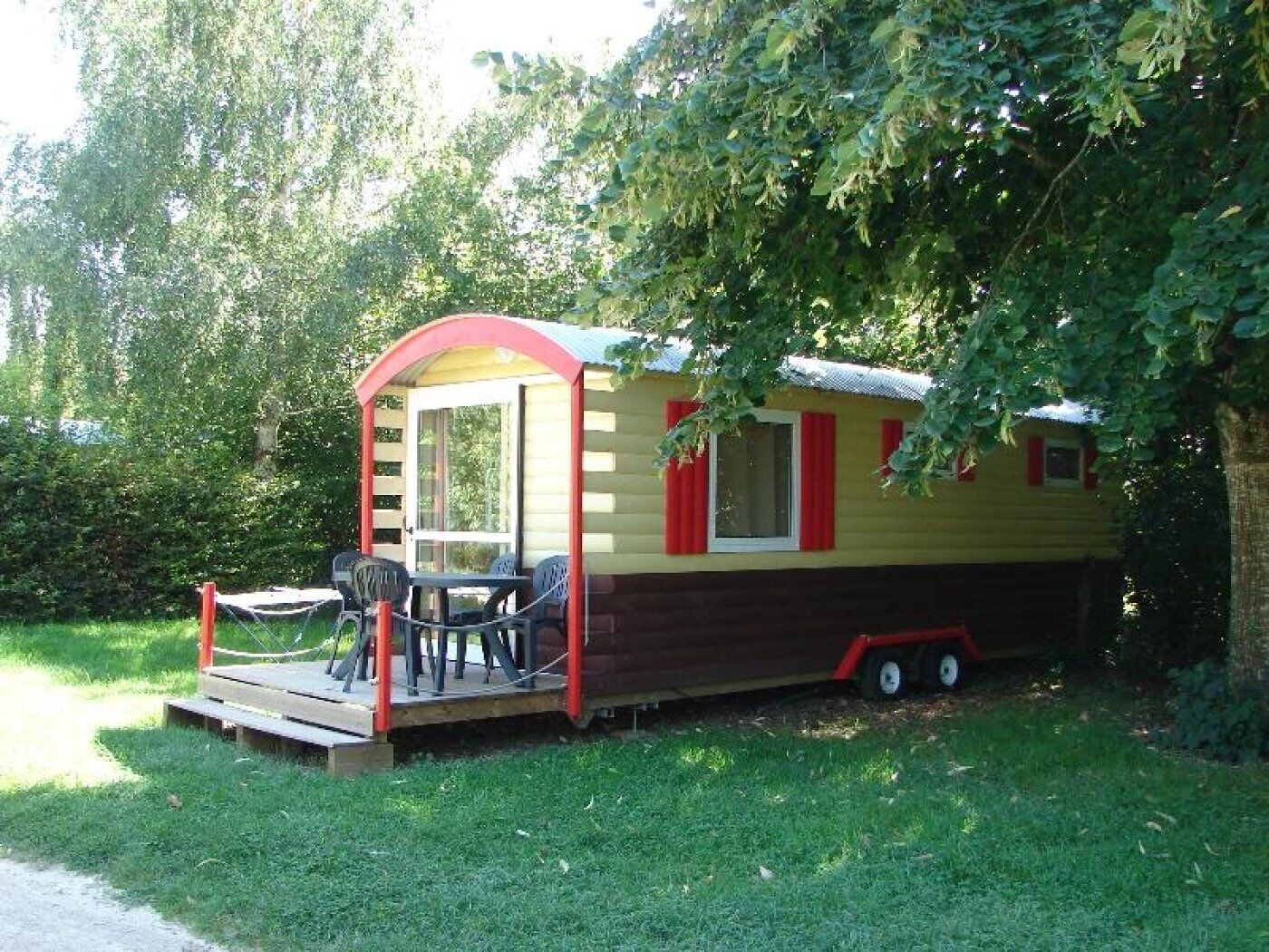 Ein kleines, eingeschossiges Mobilheim mit Veranda, Tisch und Stühlen.