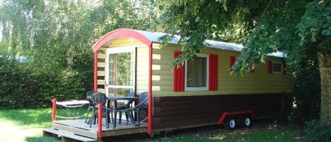 Ein kleines, eingeschossiges Mobilheim mit Veranda, Tisch und Stühlen.
