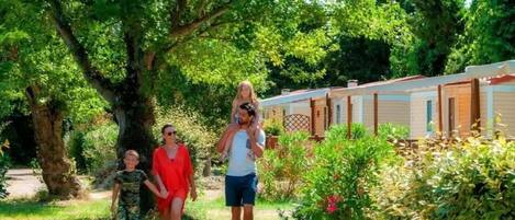 A family walking along a path with a row of mobile homes in the background.