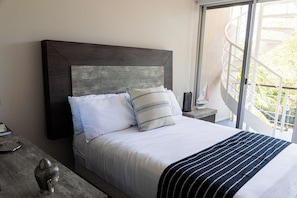 A bed with a dark headboard, white bedding, and a striped blanket. - Upscale 2BR Penthouse w/Private Rooftop (Playa del Carmen)