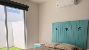 A bedroom with a bed, a nightstand, a window with a view, and an air conditioning unit. - Depa Coral- Luxory apartment with Private Beach Club (Acapulco de Juárez)
