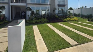 A modern multi-story building with balconies, a well-maintained lawn, and a clear sky. - Depa Coral- Luxory apartment with Private Beach Club (Acapulco de Juárez)