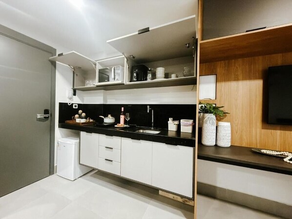 Una cocina moderna con armarios blancos, encimera negra y horno empotrado.