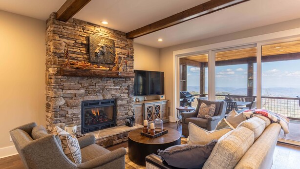 Una sala de estar con chimenea de piedra, televisor de pantalla plana, asientos cómodos y un balcón con vistas.