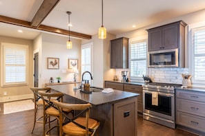 A kitchen with a central island, wooden chairs, a built-in oven, and a microwave. - The Lookout at Blue Ridge Mountain Club-amenities, seasonal pool, outdoor gas fireplace (Boone)