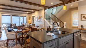 Una cocina con encimera de granito, sillas de madera, una mesa de comedor y una escalera que sube a un nivel superior.