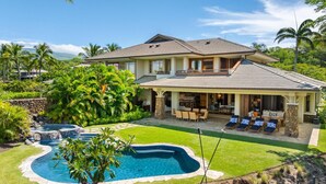 Ein großzügiges Haus mit Pool, Sitzgelegenheiten im Freien und üppiger Bepflanzung.