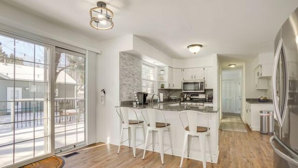 Una cocina moderna con armarios blancos, una isla central con taburetes y un refrigerador grande.