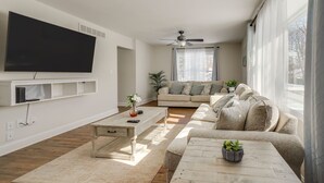 Una sala de estar con televisión de pantalla plana, un sofá, una mesa de centro y un ventilador de techo.